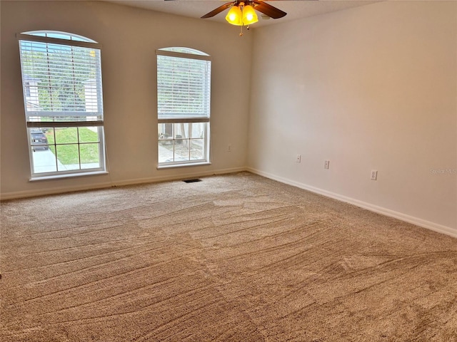 carpeted empty room featuring a healthy amount of sunlight and ceiling fan