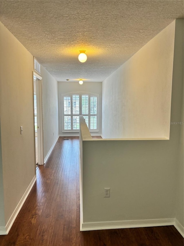 hallway with dark hardwood / wood-style floors and a textured ceiling