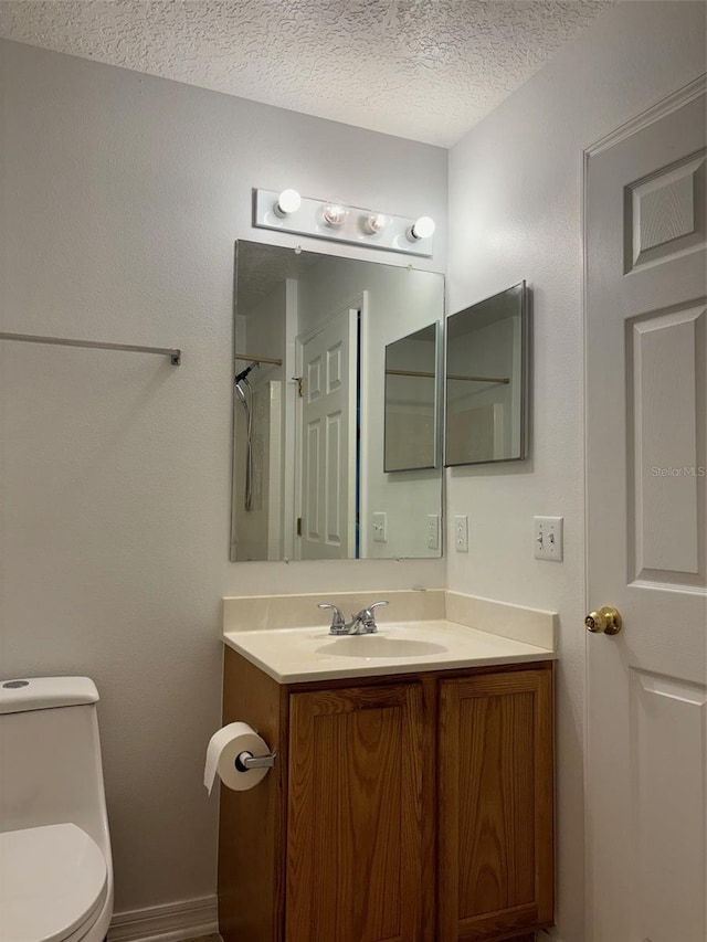 bathroom with vanity, toilet, and a textured ceiling