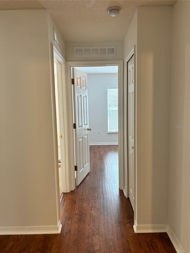 hallway featuring dark hardwood / wood-style flooring and a textured ceiling