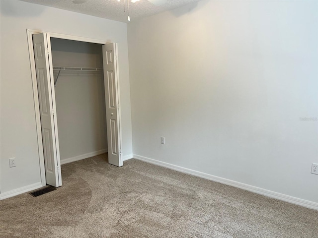 unfurnished bedroom with light colored carpet, a textured ceiling, ceiling fan, and a closet