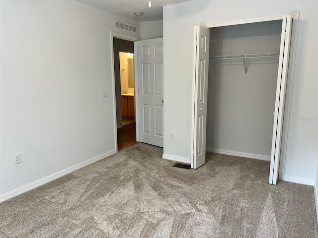 unfurnished bedroom with carpet flooring, a textured ceiling, and a closet