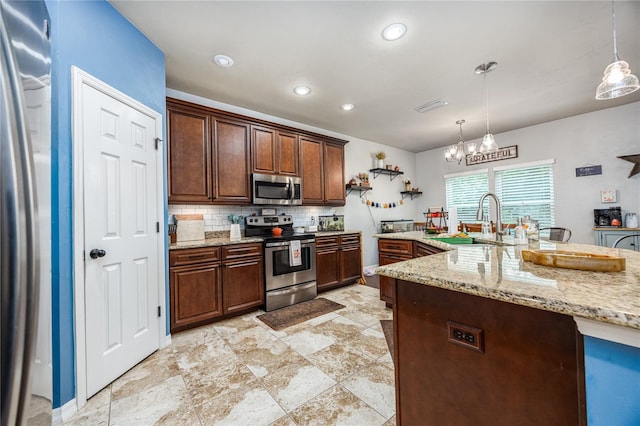 kitchen with a notable chandelier, decorative light fixtures, stainless steel appliances, sink, and decorative backsplash