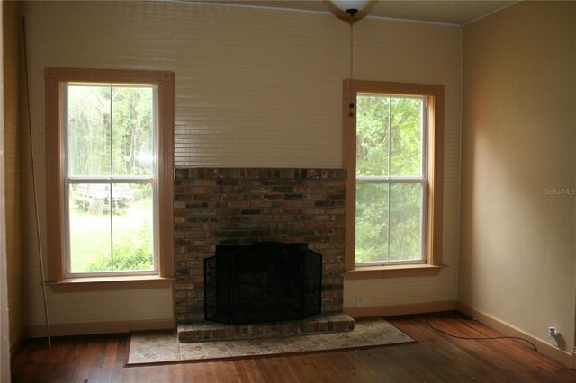 unfurnished living room with crown molding, plenty of natural light, dark hardwood / wood-style flooring, and a brick fireplace