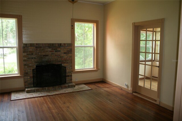 unfurnished living room with a wealth of natural light, a fireplace, and dark hardwood / wood-style floors