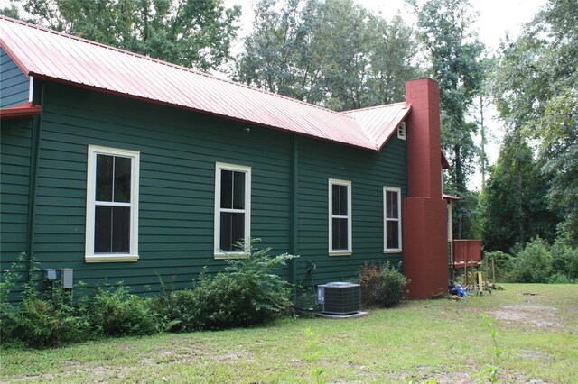 view of side of home featuring central AC unit and a yard