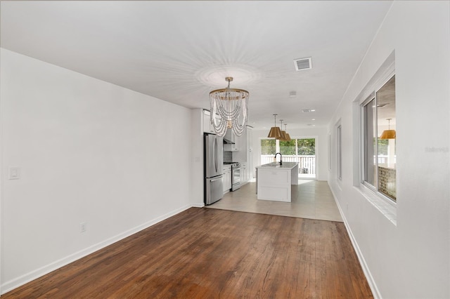 unfurnished living room with sink, a chandelier, and dark hardwood / wood-style floors