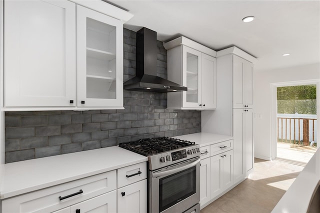 kitchen with white cabinetry, wall chimney range hood, backsplash, and high end range