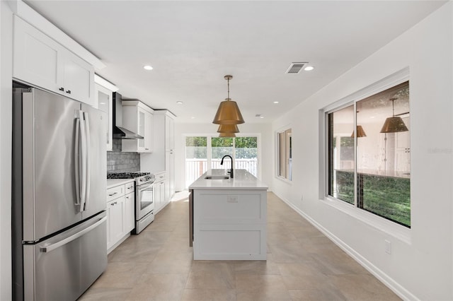 kitchen featuring decorative backsplash, appliances with stainless steel finishes, wall chimney range hood, pendant lighting, and white cabinetry