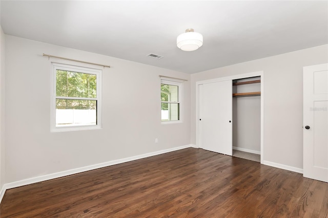 unfurnished bedroom featuring a closet, dark hardwood / wood-style flooring, and multiple windows