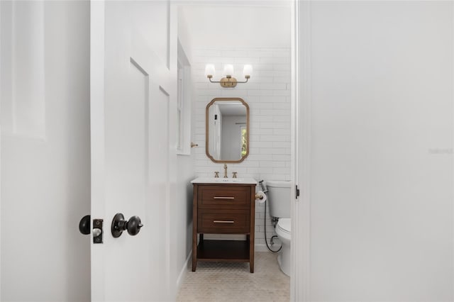 bathroom featuring tile patterned flooring, vanity, toilet, and tile walls