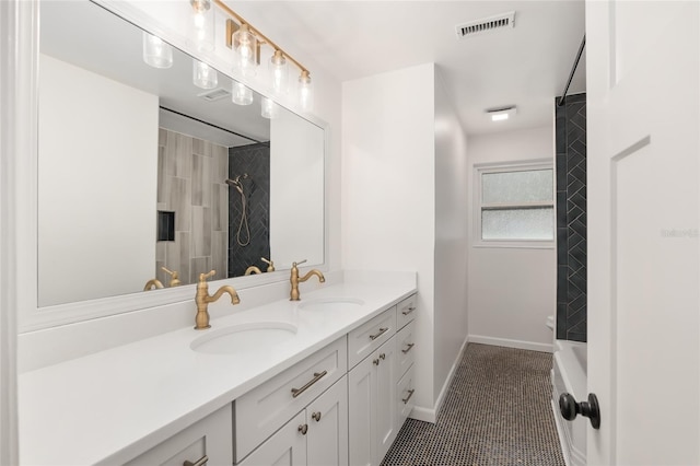 bathroom with tile patterned flooring, vanity, and tiled shower