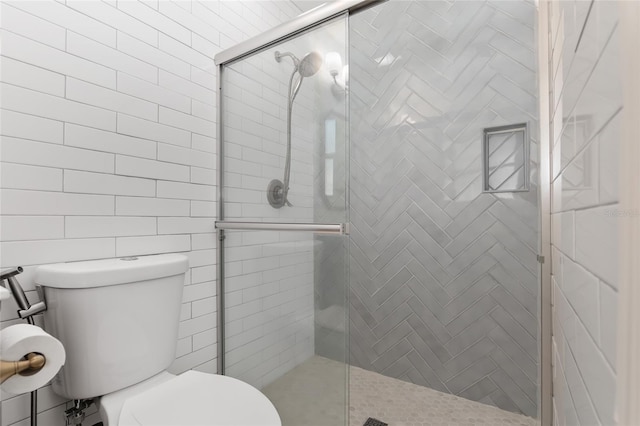 bathroom featuring toilet and a shower with shower door