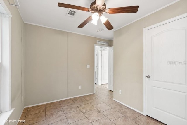 spare room featuring crown molding, light tile patterned floors, and ceiling fan