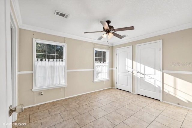 spare room featuring ceiling fan, ornamental molding, and light tile patterned flooring