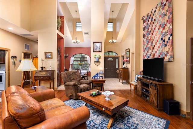 living room featuring hardwood / wood-style flooring, a towering ceiling, and an inviting chandelier