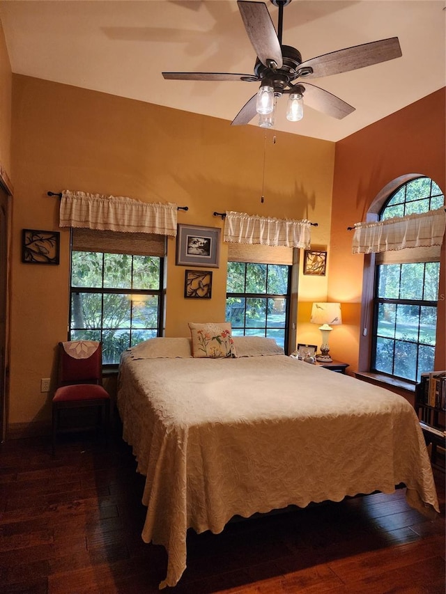 bedroom featuring ceiling fan, dark wood-type flooring, and multiple windows