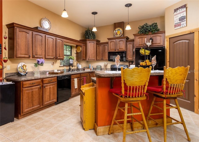 kitchen with dark stone countertops, a breakfast bar, a kitchen island, and black appliances