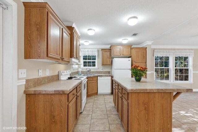 kitchen featuring sink, a center island, light tile patterned floors, ornamental molding, and white appliances