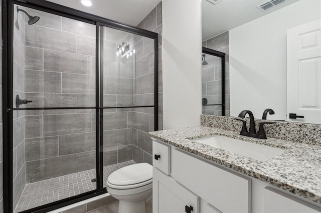 bathroom featuring a shower with door, vanity, a textured ceiling, and toilet