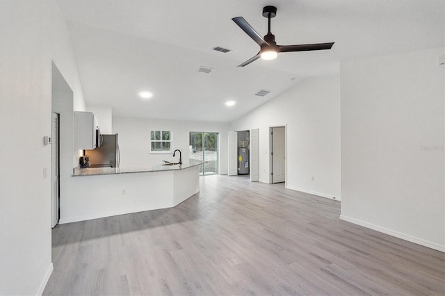 kitchen featuring kitchen peninsula, vaulted ceiling, ceiling fan, sink, and light hardwood / wood-style floors