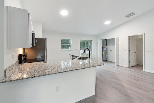 kitchen with sink, light stone counters, light hardwood / wood-style flooring, stove, and vaulted ceiling