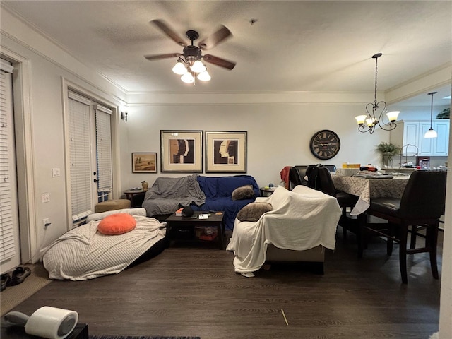 living room with ornamental molding, ceiling fan with notable chandelier, and dark hardwood / wood-style flooring