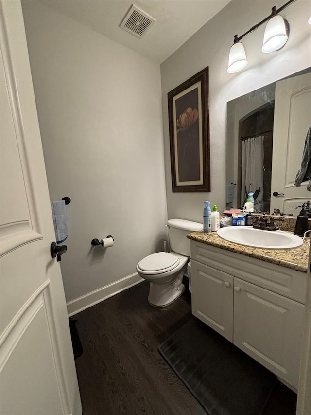 bathroom with hardwood / wood-style flooring, vanity, and toilet