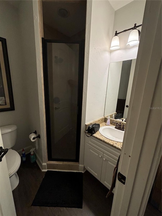 bathroom with walk in shower, vanity, hardwood / wood-style floors, and toilet