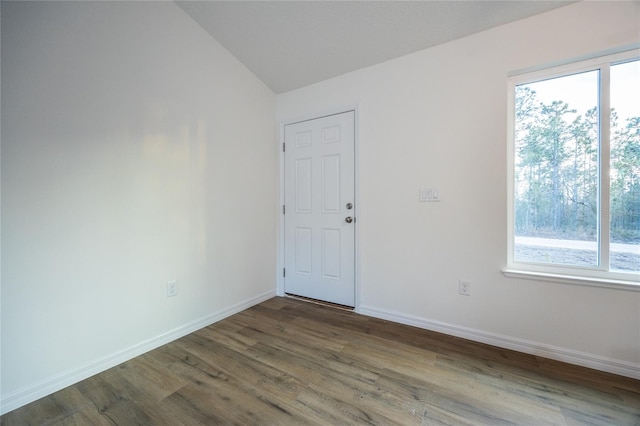 spare room featuring wood-type flooring and vaulted ceiling