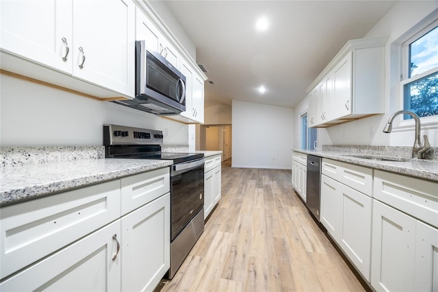 kitchen featuring appliances with stainless steel finishes, sink, white cabinets, and light hardwood / wood-style flooring