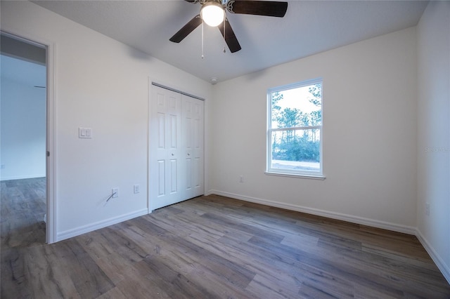 unfurnished bedroom featuring hardwood / wood-style floors, a closet, and ceiling fan