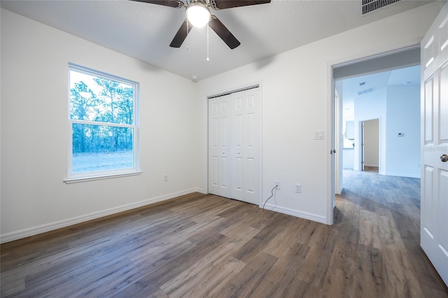 unfurnished bedroom featuring dark wood-type flooring, ceiling fan, and a closet