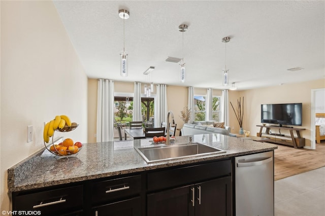 kitchen featuring stone counters, pendant lighting, sink, stainless steel dishwasher, and a textured ceiling