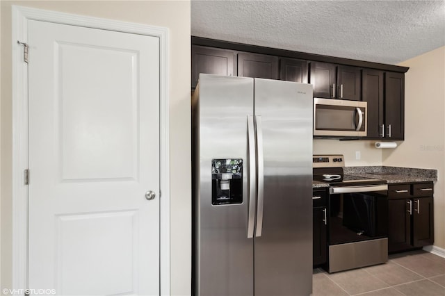 kitchen with appliances with stainless steel finishes, a textured ceiling, dark brown cabinets, and light tile patterned floors