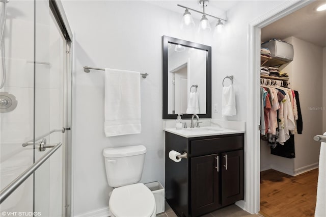 bathroom with walk in shower, wood-type flooring, toilet, and vanity