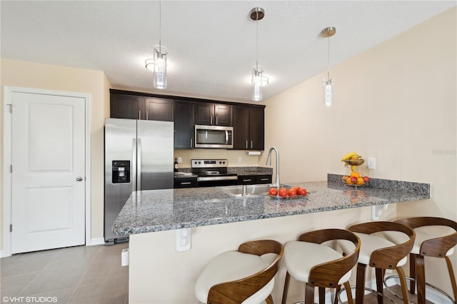 kitchen featuring decorative light fixtures, light tile patterned floors, kitchen peninsula, stainless steel appliances, and a textured ceiling