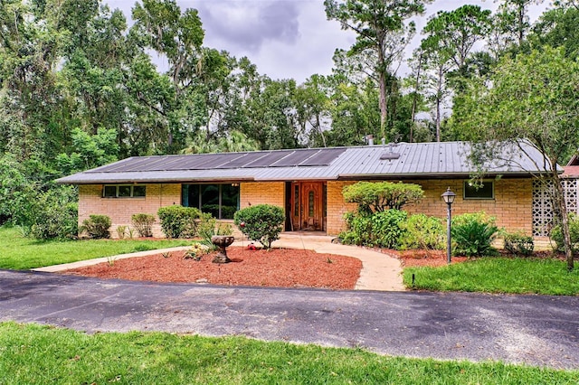 ranch-style home featuring brick siding, metal roof, and a front yard