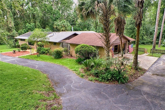 ranch-style home with brick siding, concrete driveway, a front lawn, and fence