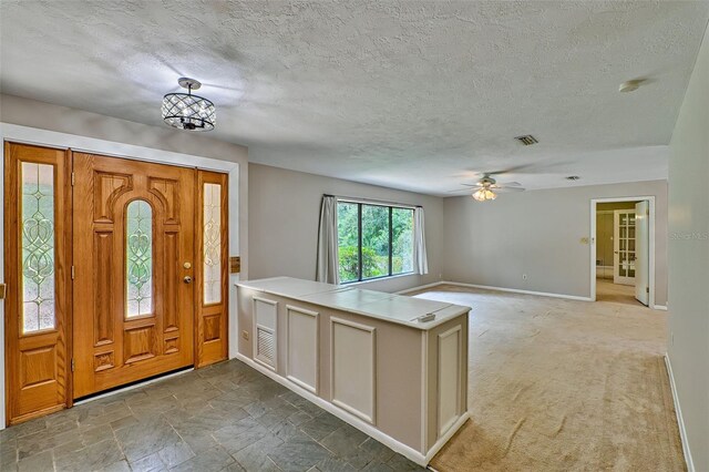 entryway with visible vents, ceiling fan with notable chandelier, stone finish flooring, a textured ceiling, and baseboards