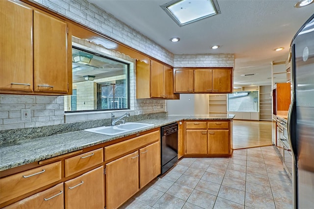 kitchen with black dishwasher, brown cabinets, a peninsula, light tile patterned flooring, and a sink