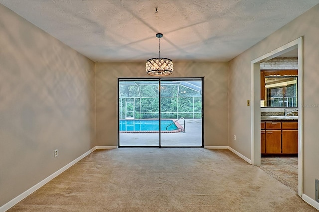 spare room with a textured ceiling, a sink, baseboards, and light carpet