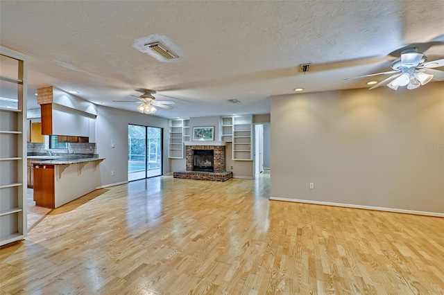 unfurnished living room with a textured ceiling, light wood-style floors, visible vents, and ceiling fan