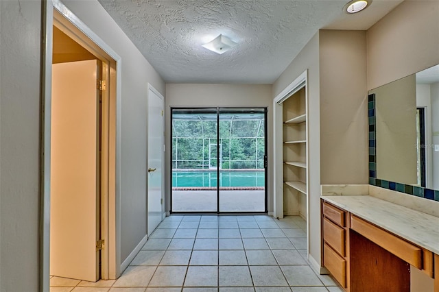 bathroom with tile patterned flooring, baseboards, and a textured ceiling