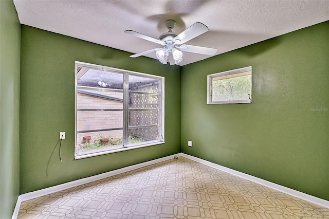 spare room with tile patterned floors, ceiling fan, a textured ceiling, and baseboards