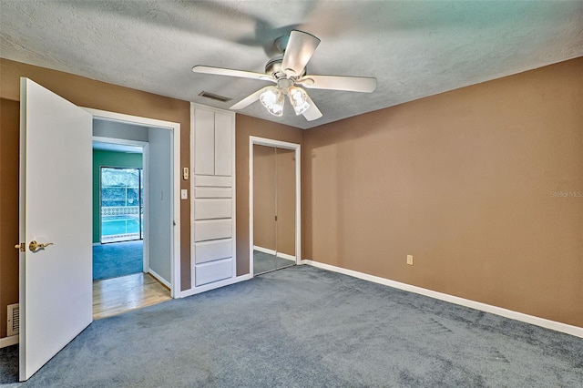 unfurnished bedroom featuring carpet flooring, a textured ceiling, and visible vents