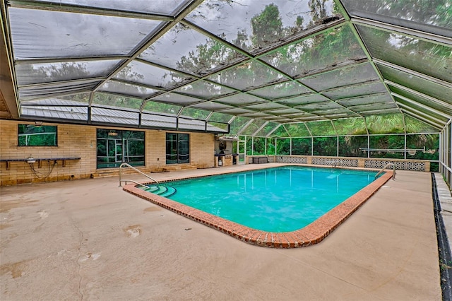 outdoor pool featuring glass enclosure and a patio