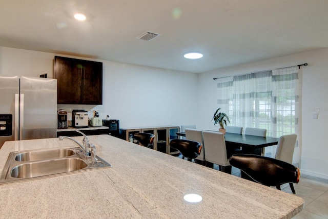 kitchen with dark brown cabinetry, sink, and stainless steel fridge