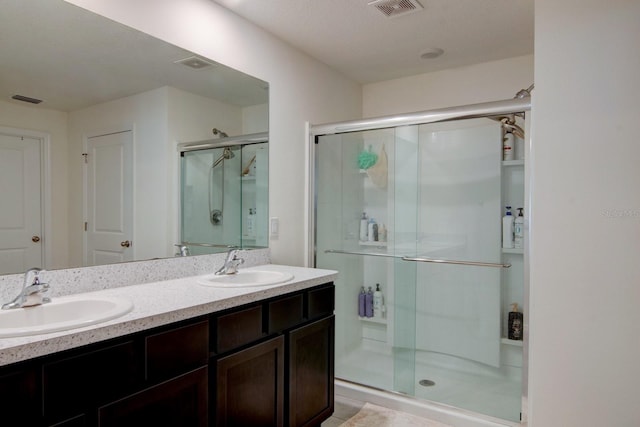 bathroom with a textured ceiling, vanity, and an enclosed shower