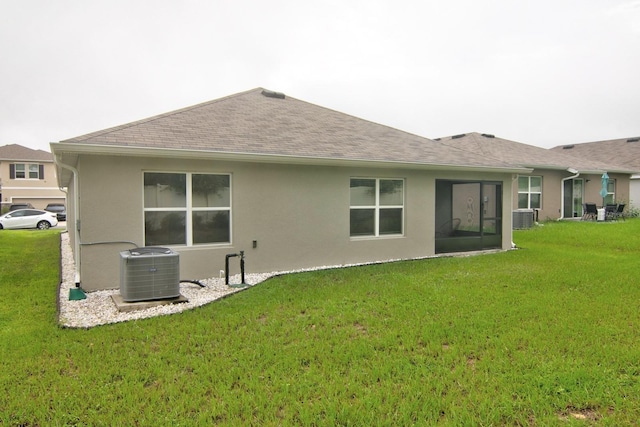 rear view of house featuring central air condition unit and a yard